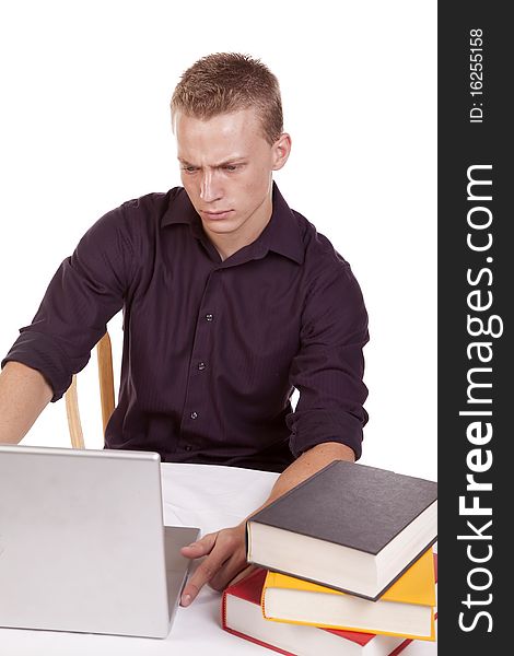A young man sitting and working on his laptop with a stack of books. A young man sitting and working on his laptop with a stack of books.