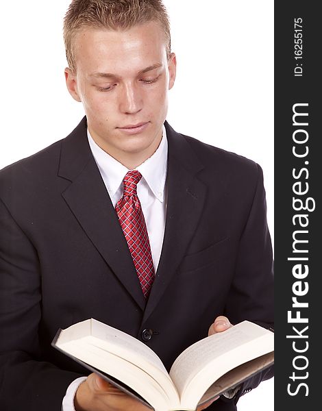 A young businessman in a suit reading and studing out of a text book. A young businessman in a suit reading and studing out of a text book.