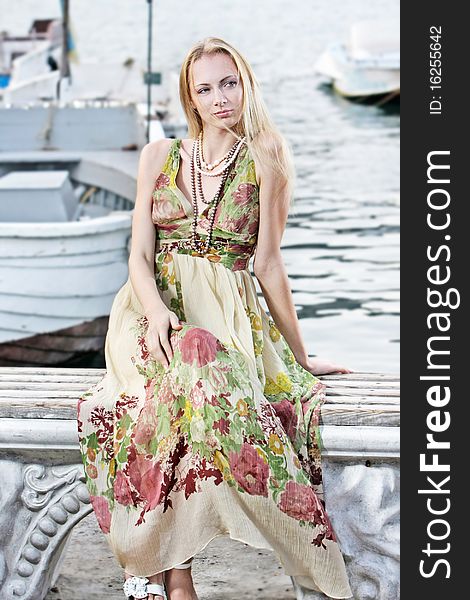 Young attractive woman sitting on pier background. Young attractive woman sitting on pier background