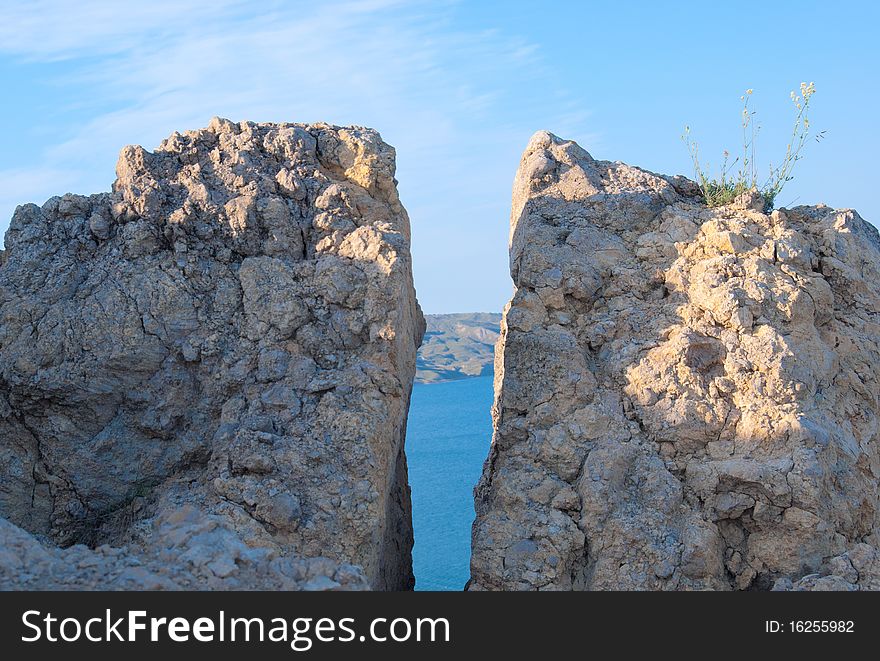 Crack in a rock through which the sea and the sky is visible