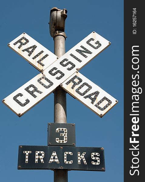 A Railroad Crossing, 3 Tracks traffic sign against a blue sky. A Railroad Crossing, 3 Tracks traffic sign against a blue sky