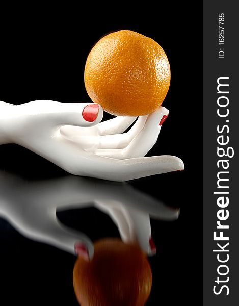 Orange in the white hand with reflection. Balck background. Orange in the white hand with reflection. Balck background.