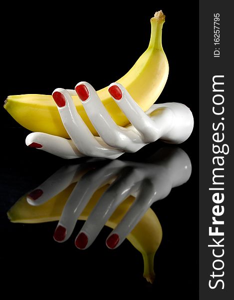 Hand and banana with reflection. Black background.