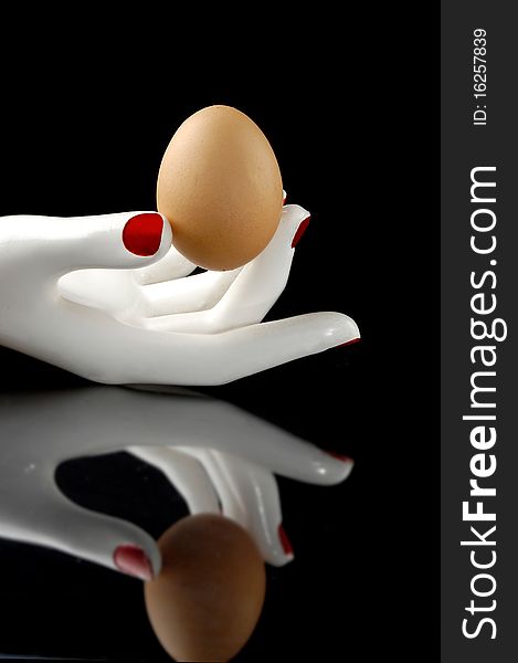 Egg in the white hand with reflection. Black background. Egg in the white hand with reflection. Black background.