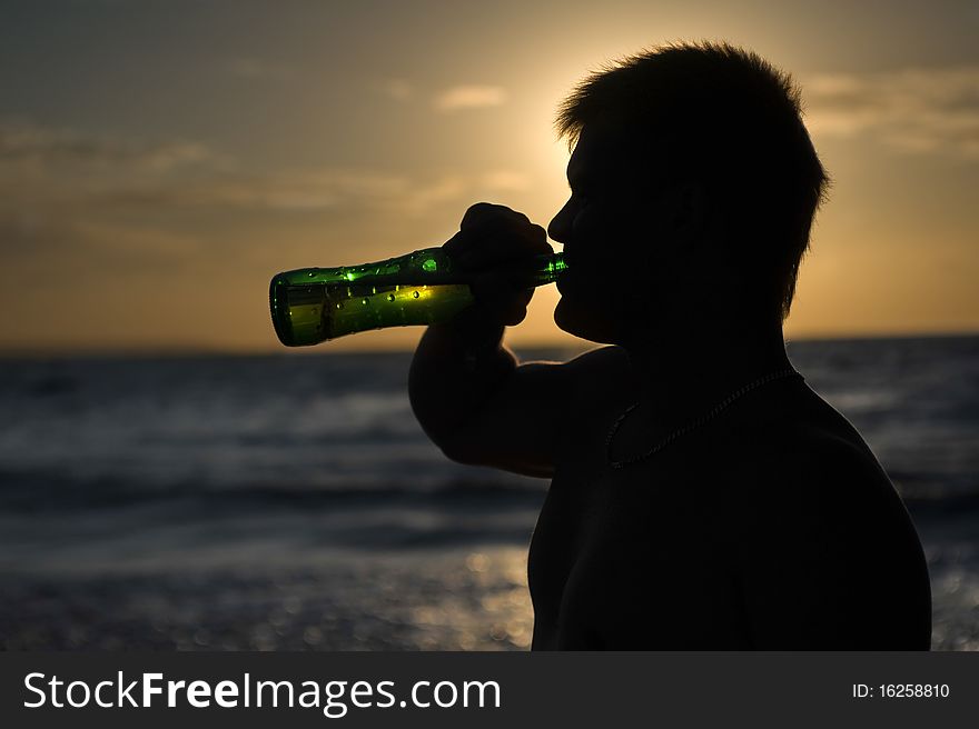 Silhouette of a man drinking beer on the on the beach