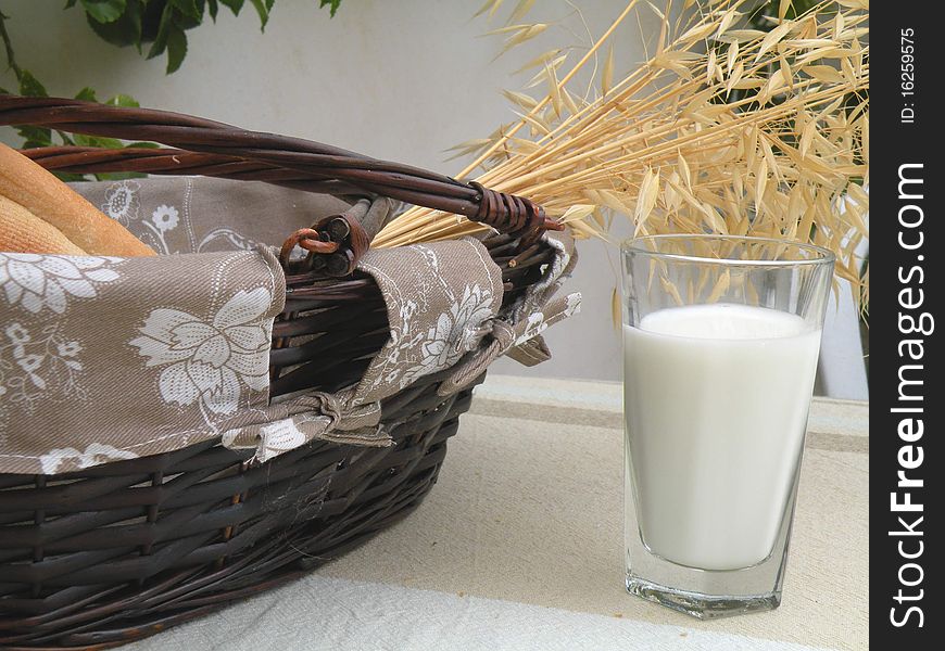 Basket of white rolls and a glass of milk decorated spikelets