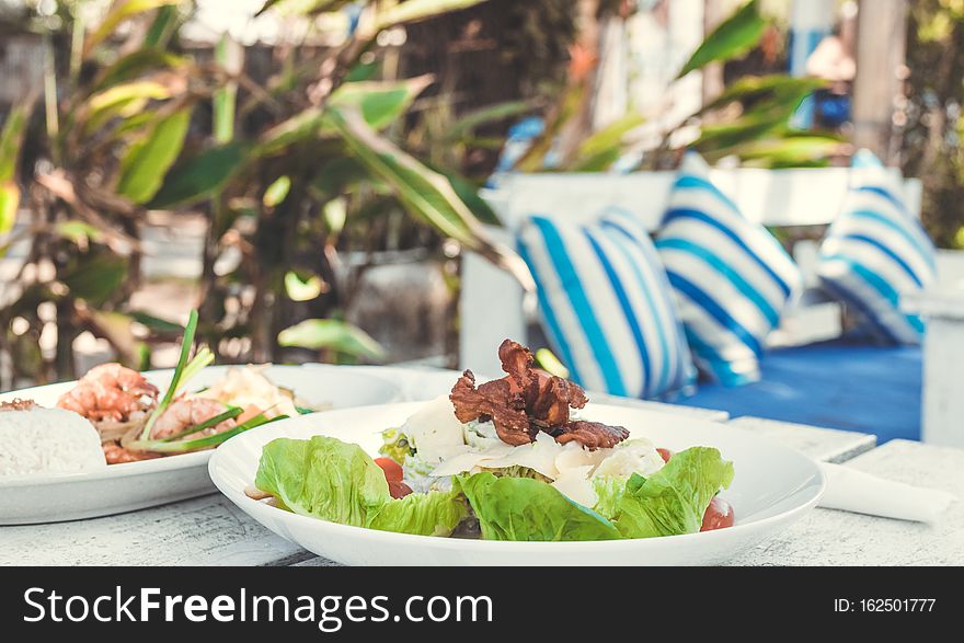 Caesar Salad on a white wooden table in the beach cafe, Bali island. Indonesia.