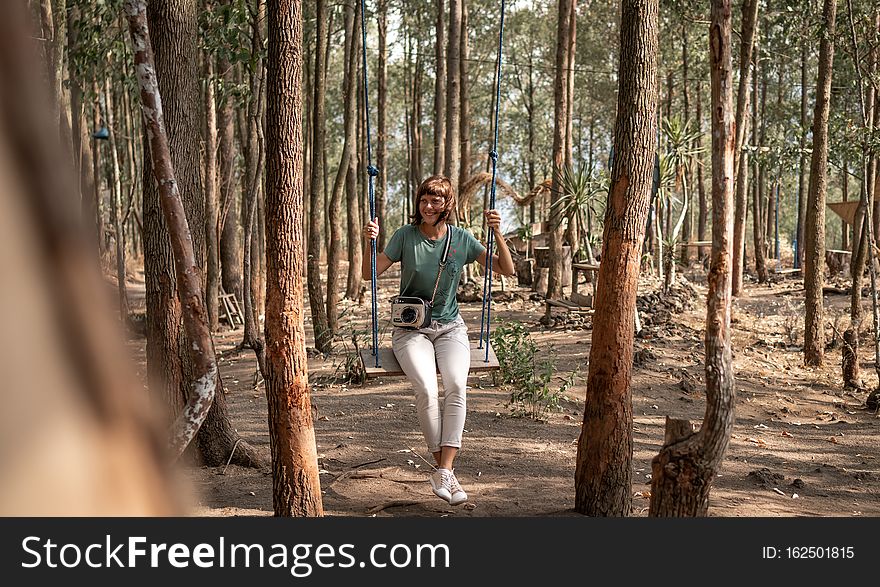 Young woman on the swing in the forest. Bali island.