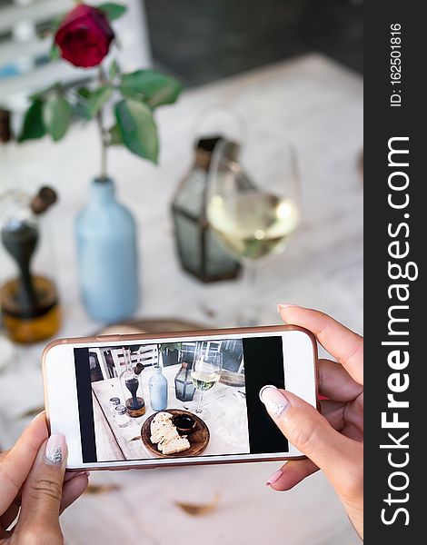 Woman taking photo of bread and wine on her smartphone in restaurant. Bali.