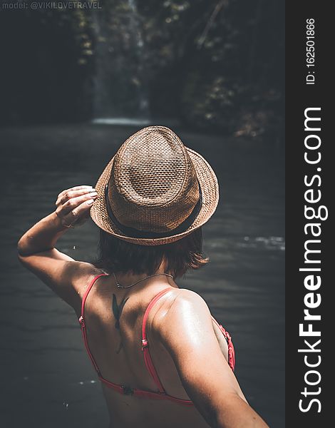 Rear view of young woman tourist with straw hat and red swimsuit in the deep jungle. Real adventure concept. Bali island.