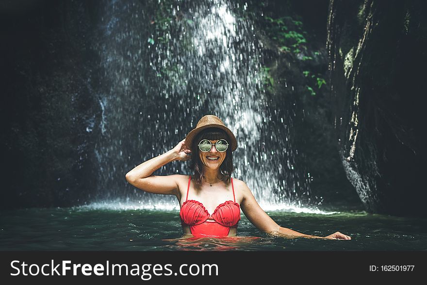 Young woman tourist in the deep jungle with waterfall. Real adventure concept. Bali island. Indonesia.