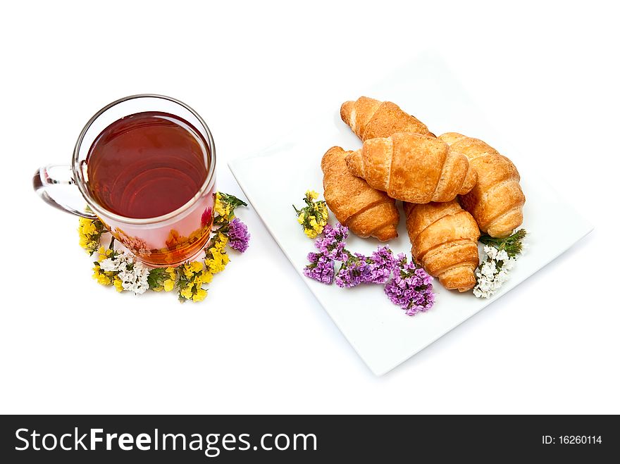 Croissants and hot tea with flowers isolated on white background