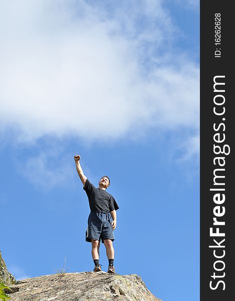 A young man stands on a cliff top