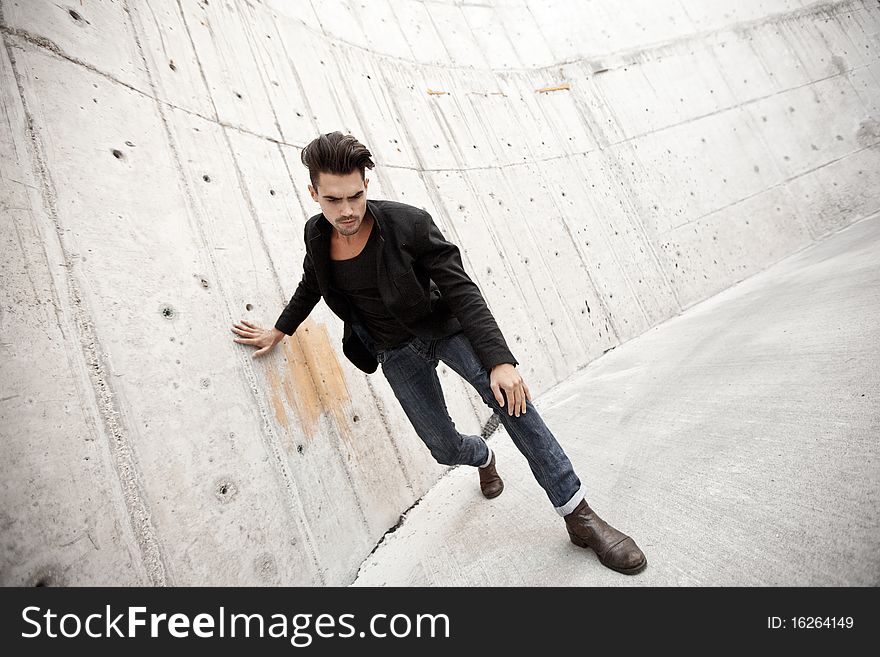 Attractive man dressed in jeans and boots in a grungy scenery