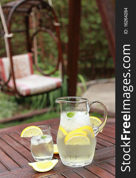 Pitcher and glasses of fresh lemonade in the garden. Pitcher and glasses of fresh lemonade in the garden