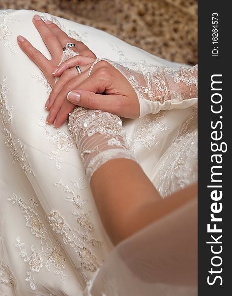 Close-up photo of the bride's hands in white gloves