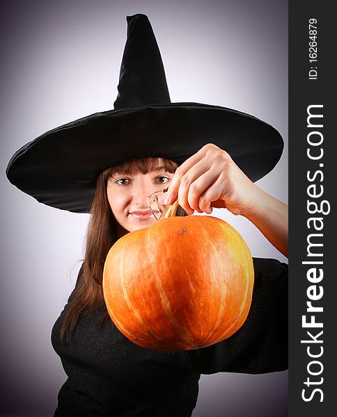 Young witch holding a pumpkin (focus on the pumpkin)
