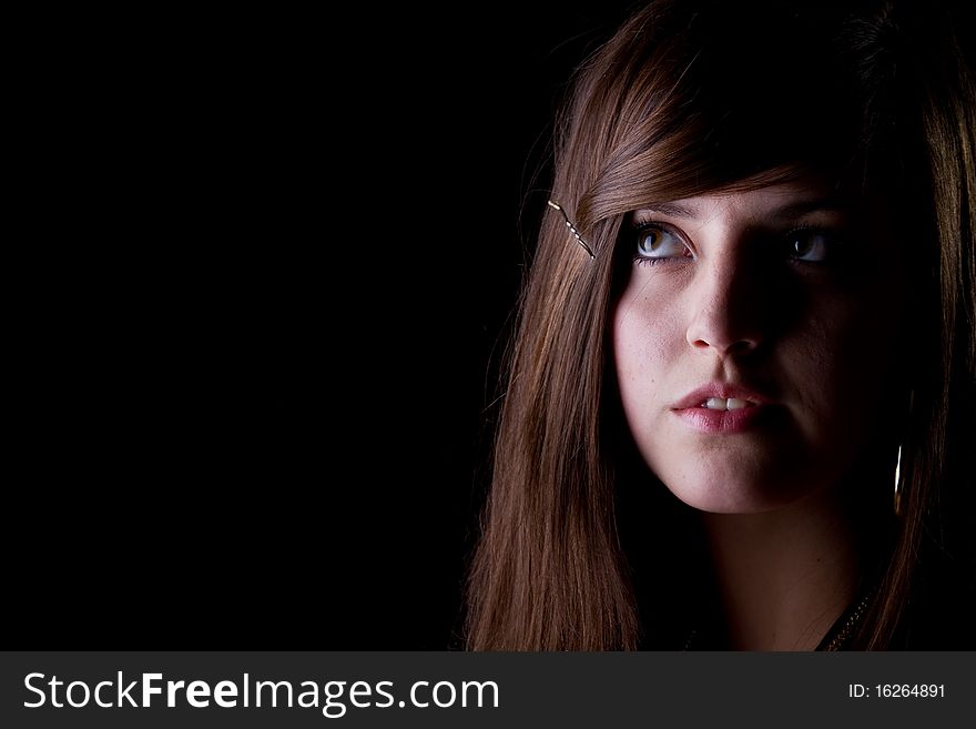 Teenage girl is looking in a corner isolated over black background. Teenage girl is looking in a corner isolated over black background.