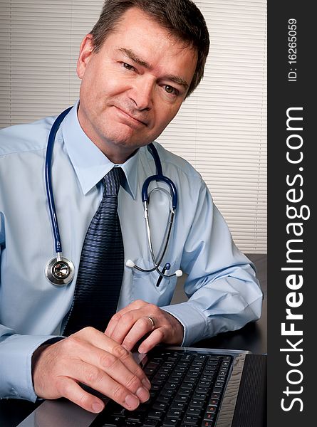 Physician at desk in surgery looks at camera confidently. Physician at desk in surgery looks at camera confidently.