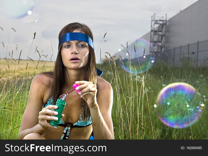 Wistful young woman blowing soap bubbles in summer day