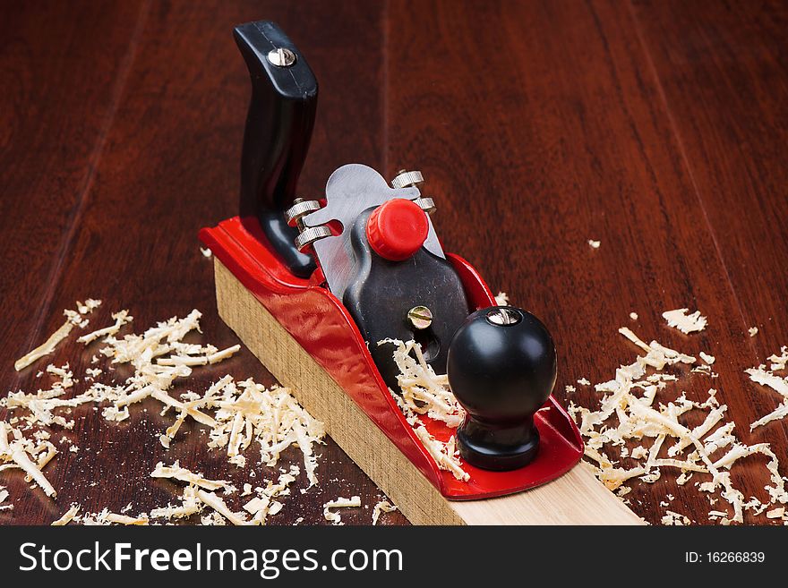 Red plane on brick and shavings on dark wooden background