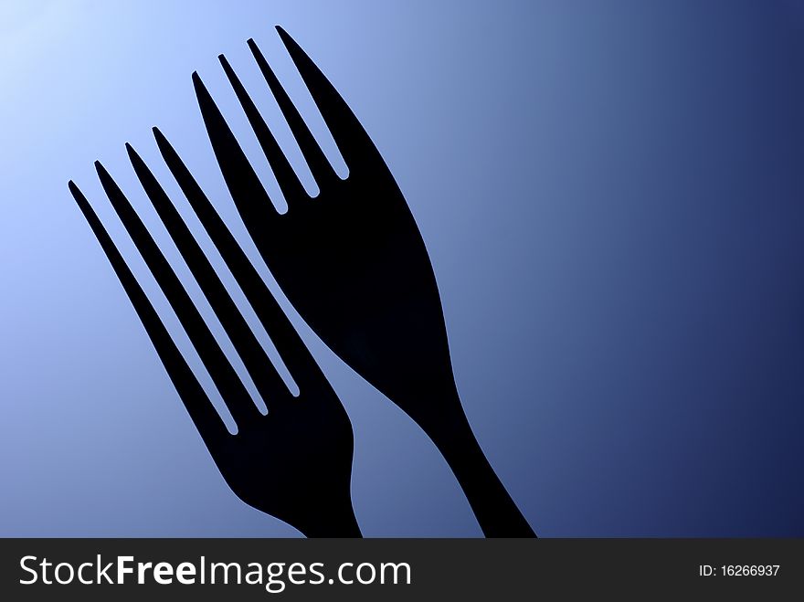 Black silhouette of the two table forks on a blue background