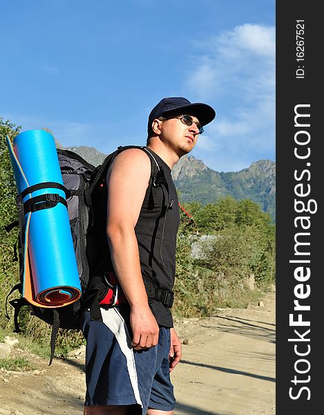 Tourist with a large backpack is a high mountain, on the road, photos in profile