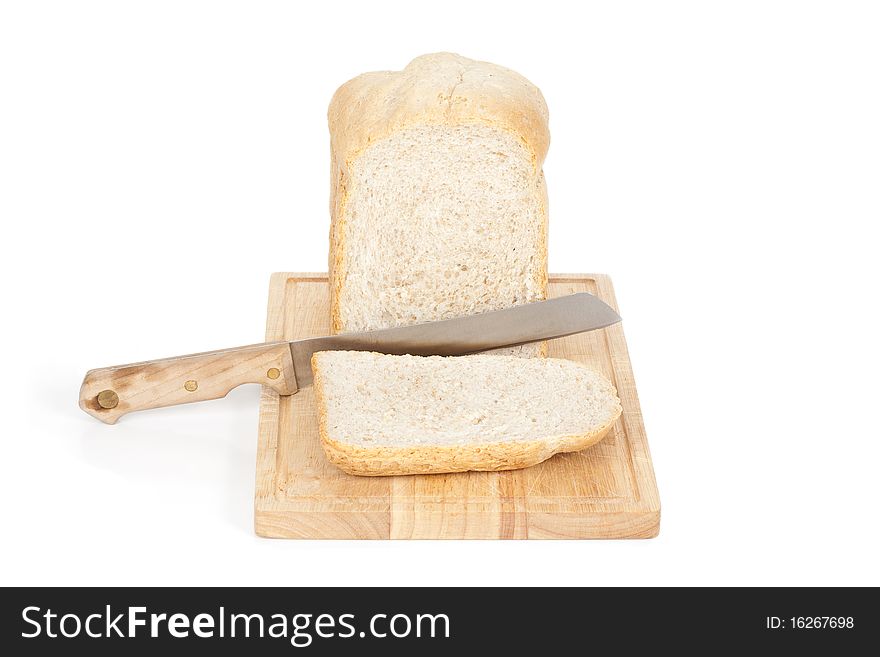 A direct angled studio view of a loaf of homemade bread and a slice on a wooden breadboard with a bread knife. A direct angled studio view of a loaf of homemade bread and a slice on a wooden breadboard with a bread knife.