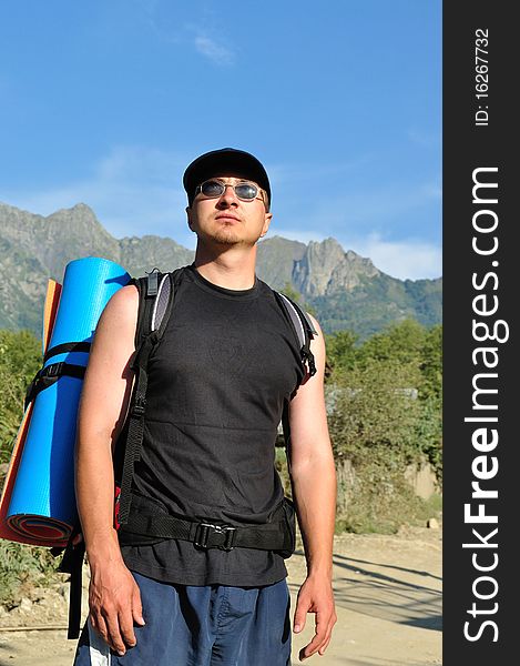 Tourist with a large backpack is a high mountain, on the way, full-face photos