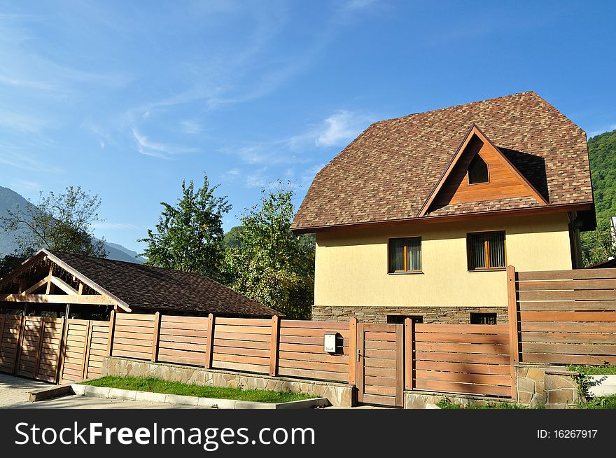 Beautiful big house with a wooden fence on the blue sky background