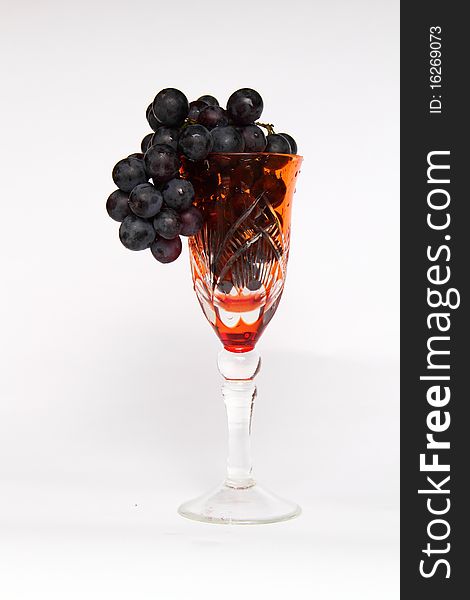 Black grapes in a glass of red glass. white background. high quality