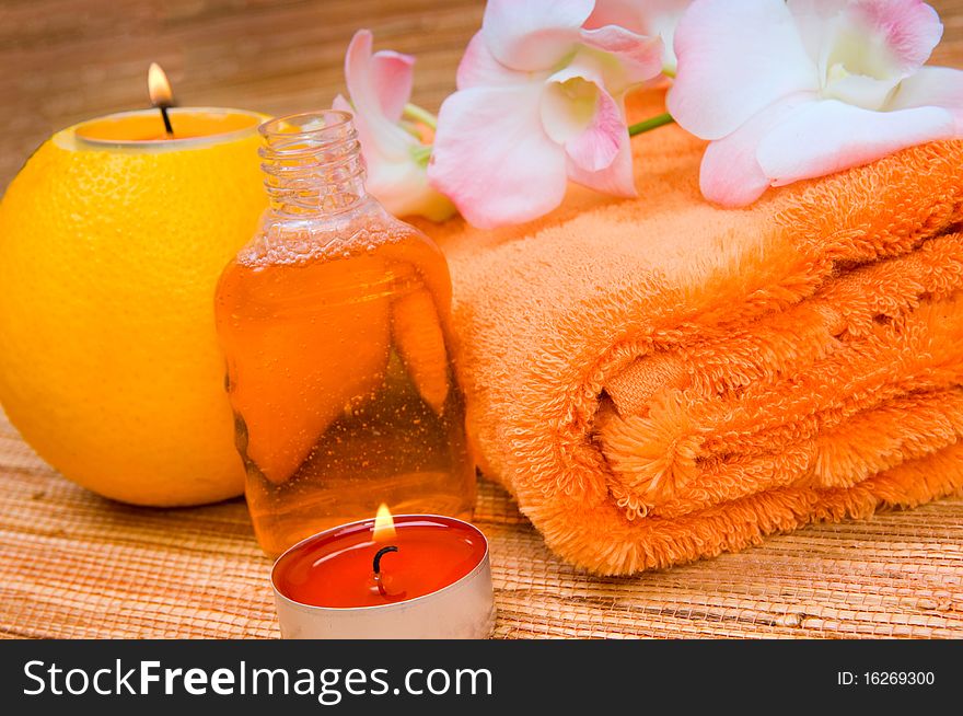 Orange towel, flower and a burning candle in citrus. Orange towel, flower and a burning candle in citrus