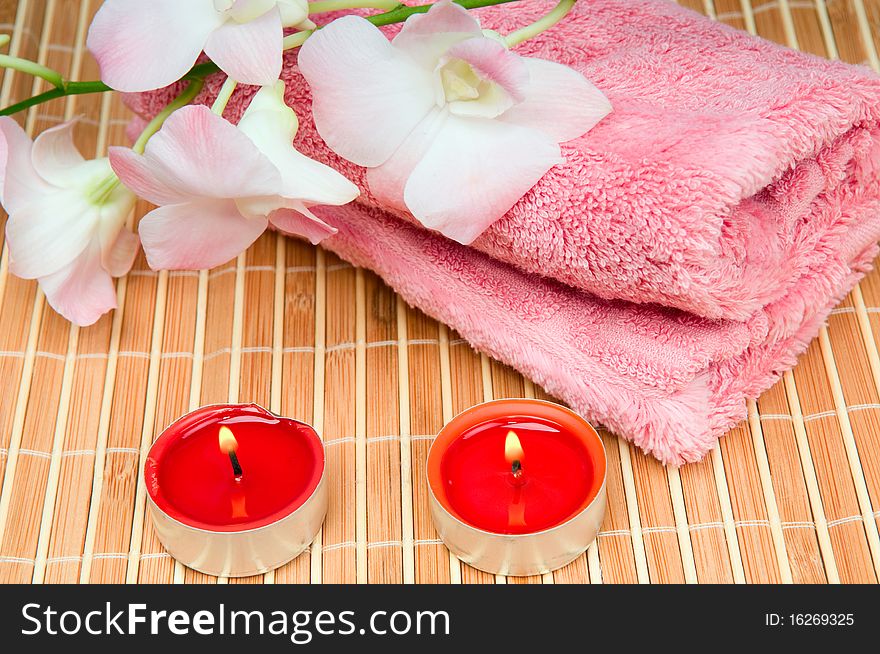 Pink towel, flower and a burning candle. Pink towel, flower and a burning candle