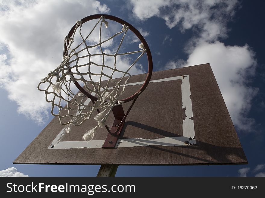 Basketball hoop outside with cloudy sky in the background