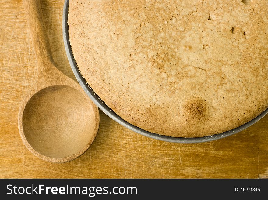 Fresh pie and spoon on a wooden cutting board