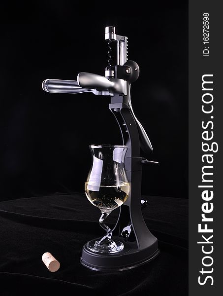 Modern Wine opener made from hard plastic and metal, with a glass of white wine and a cork, on a black background