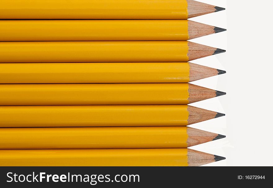 Eight sharpened yellow pencils stacked horizontally against a clean white background. Eight sharpened yellow pencils stacked horizontally against a clean white background