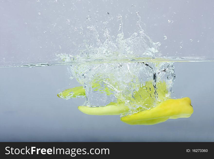 Green chilli thrown in water with gray background