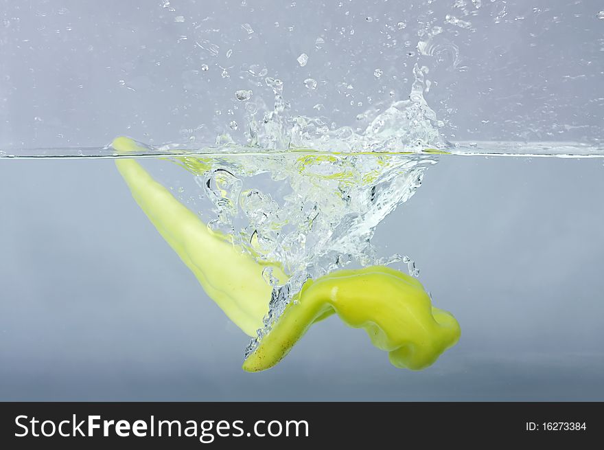 Green chilli thrown in water with gray background