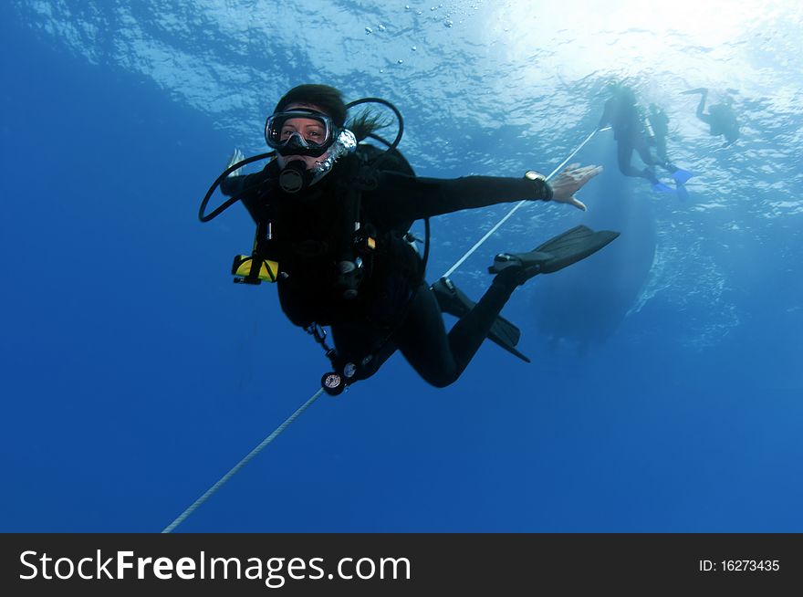 A female diver following an anchor line down to the bottom of the ocean