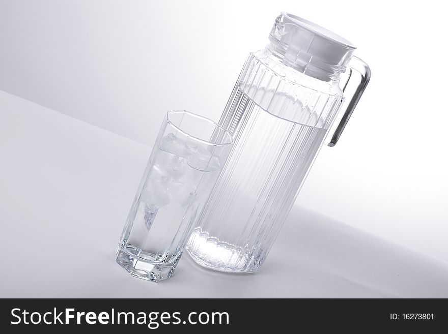 Series. Pitcher and glass with ice cubes of mineral water