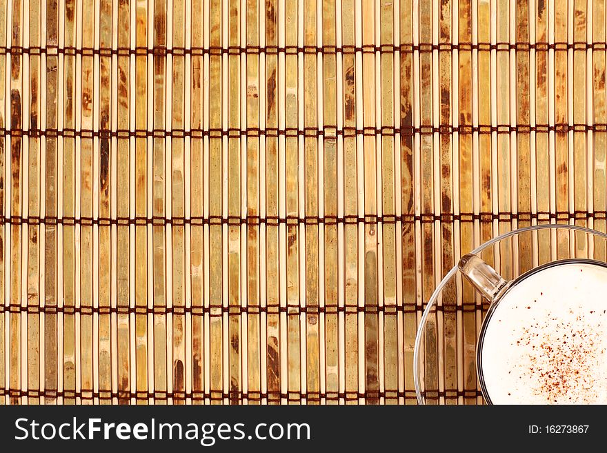 Cup of coffee and beans on bamboo mat