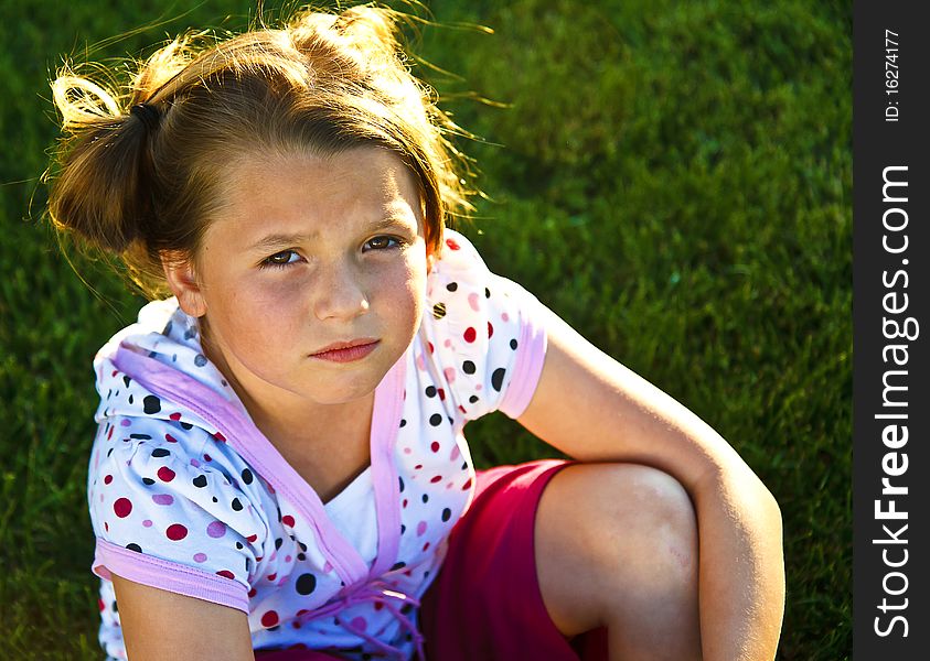 Cute little girl wearing polka dots looking unhappy outdoors. Cute little girl wearing polka dots looking unhappy outdoors.