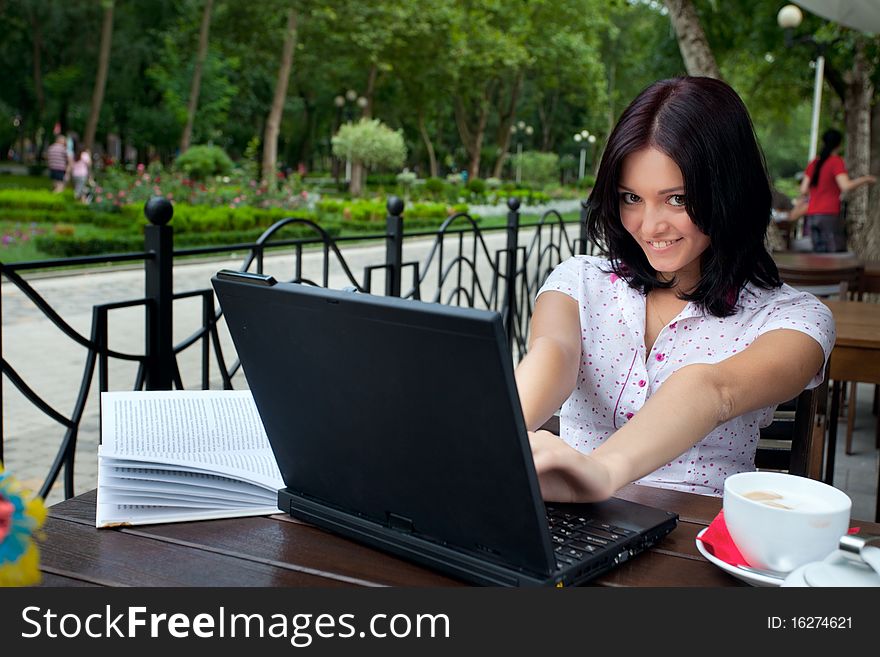 Young beautiful student girl with laptop and cup of coffee in cafe. Young beautiful student girl with laptop and cup of coffee in cafe