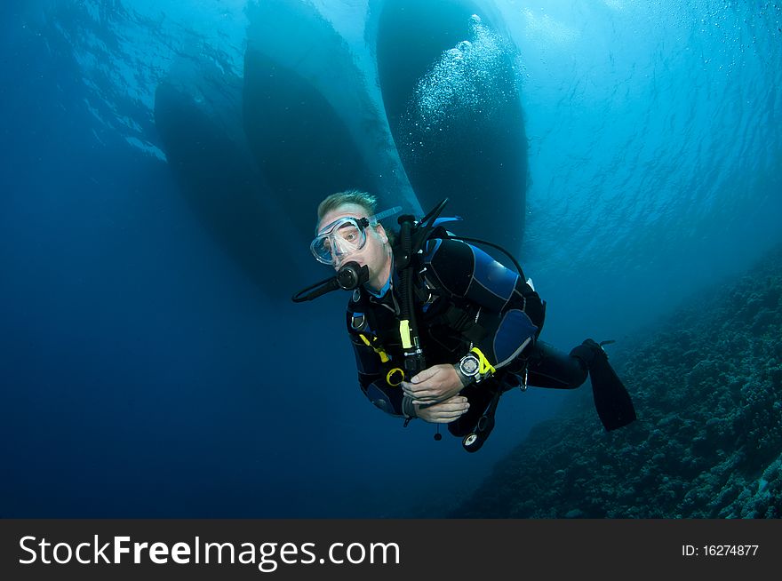 Scuba diver swims under boats