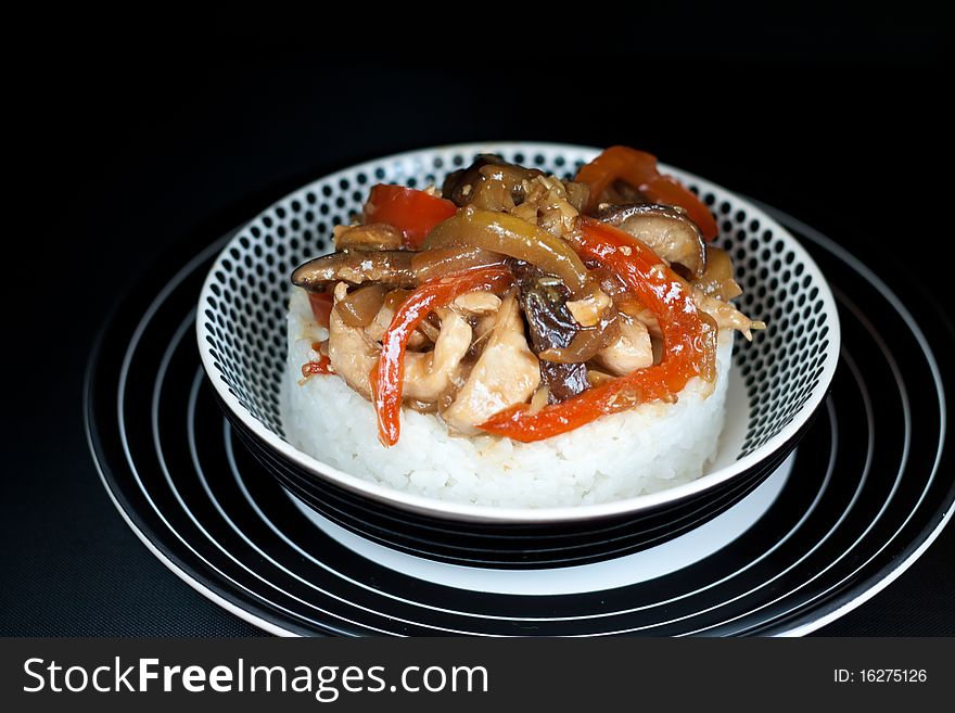 Rice with stir fry chiken and vegetables over black background. Rice with stir fry chiken and vegetables over black background