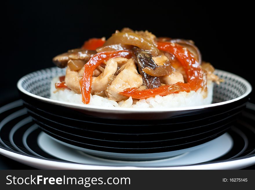 Rice with stir fry chiken and vegetables over black background. Rice with stir fry chiken and vegetables over black background