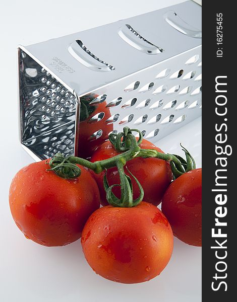 Red tomatoes and grater on white background