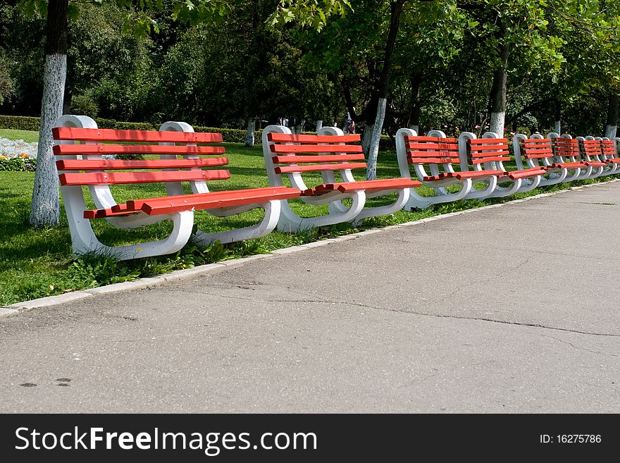 Row of red empty park benches. Row of red empty park benches