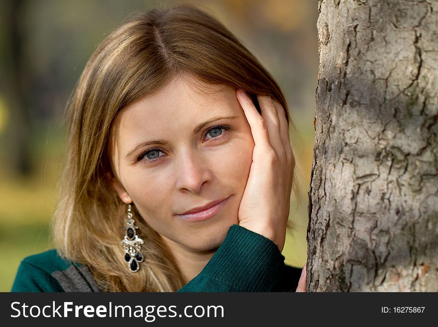 Head portrait of a blonde woman near a tree outdoor. Head portrait of a blonde woman near a tree outdoor